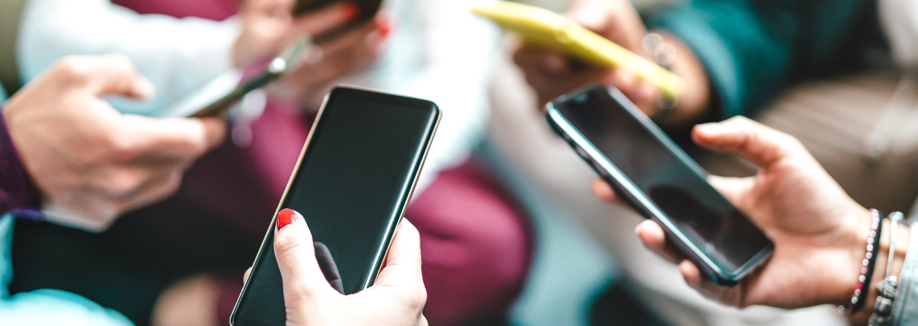  Close-up of several people holding and using smartphones, focusing on their hands and devices.