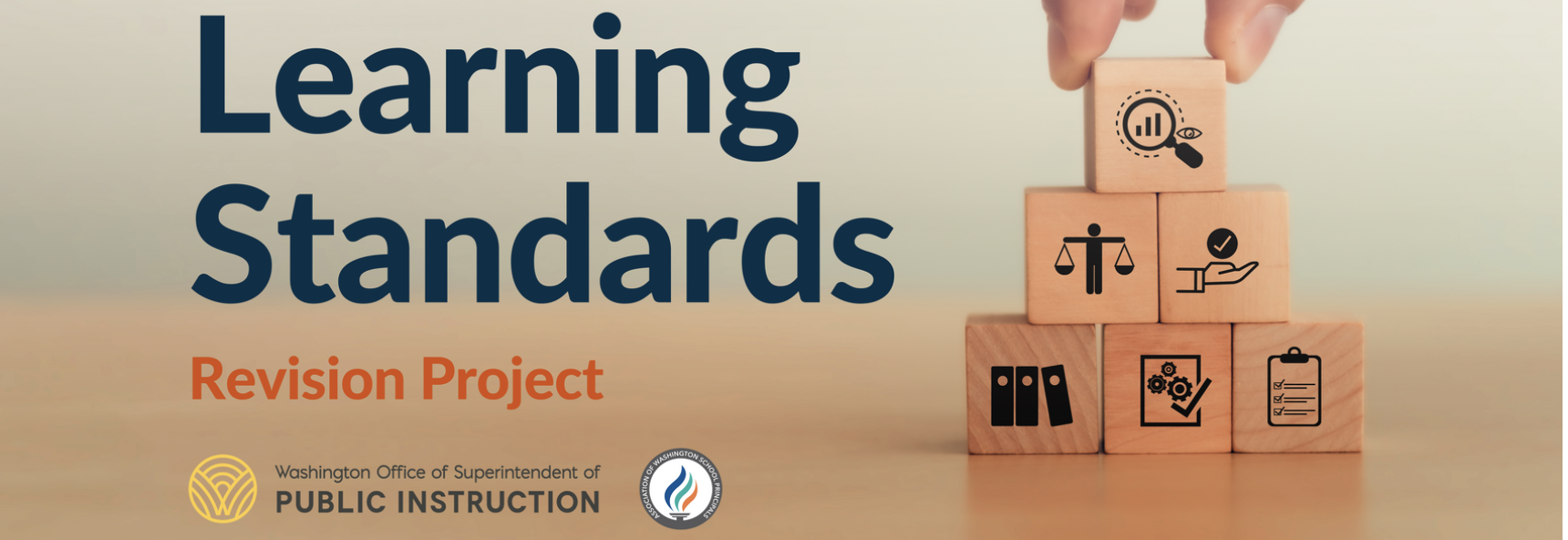 Image with title 'Learning Standards Revision Project.' Wooden blocks stacked in a pyramid feature icons like a magnifying glass, scales of justice, a hand with a checkmark, folders, gears, and a checklist. Logos for OSPI and AWSP logos are at the bottom.