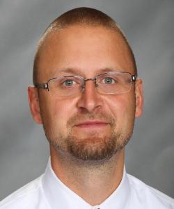 Drake_Travis-headshot wearing a white collared shirt and glasses