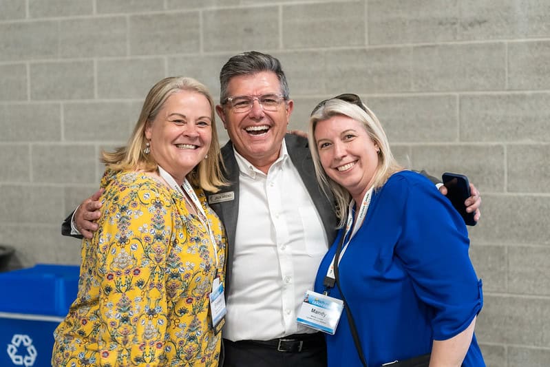 a photo of two woman on each side of a man, all happy and smiling at the camera
