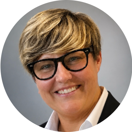 Headshot of Andrea Dixon-Hundredmark smiling, wearing black-framed glasses, a black blazer, and a white collared shirt, with short, blonde-highlighted hair.