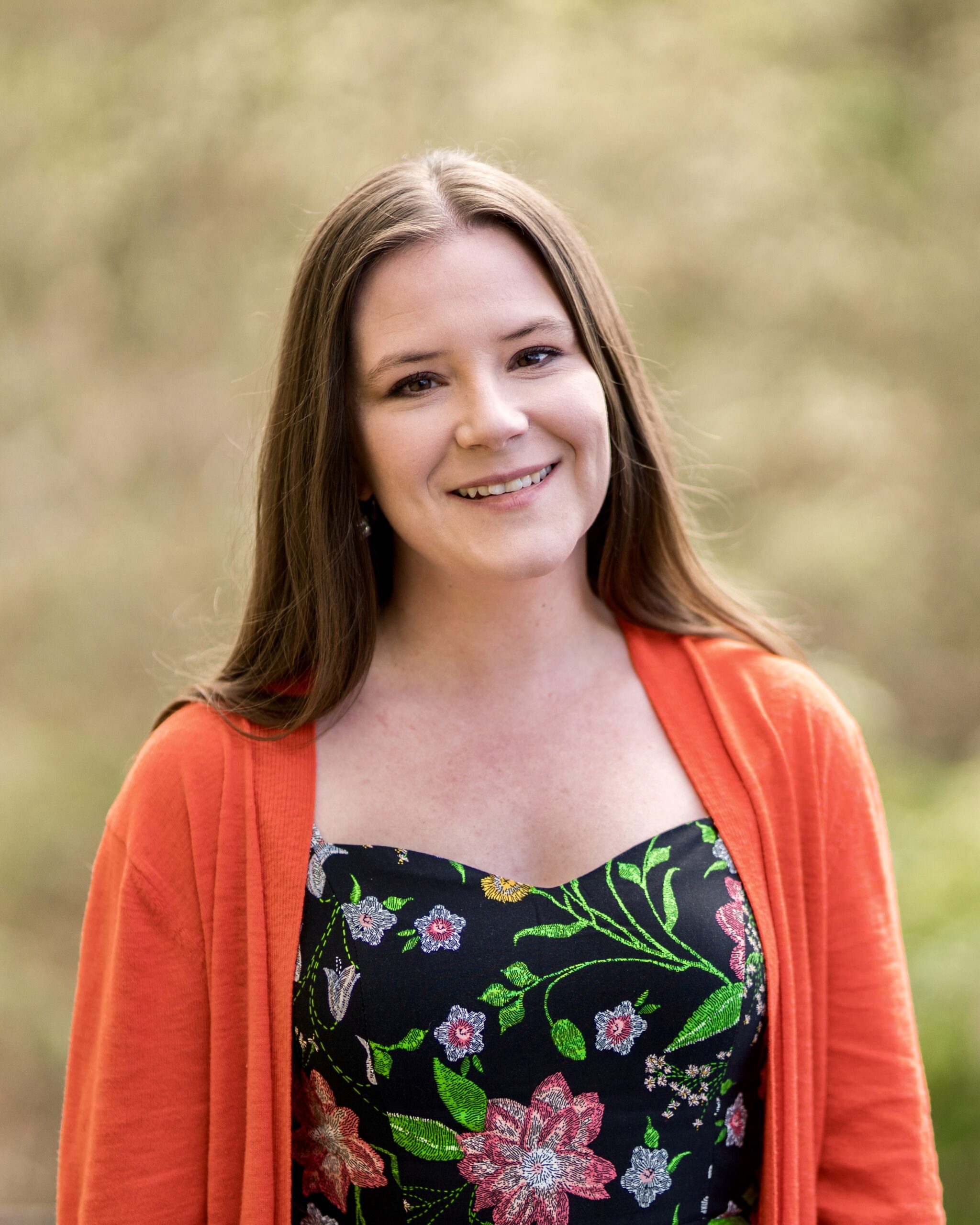 An image of a woman in a black floral dress with orange sweater