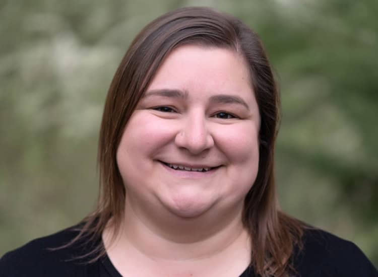 a headshot of a brunette woman wearing a black shirt