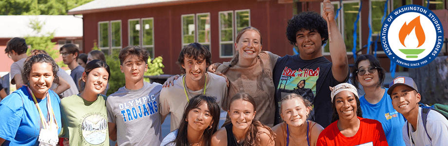 Diverse group of smiling teens posing outdoors in front of a camp building with the AWSL logo on the side.