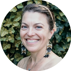 A smiling woman with a headband and long earrings.