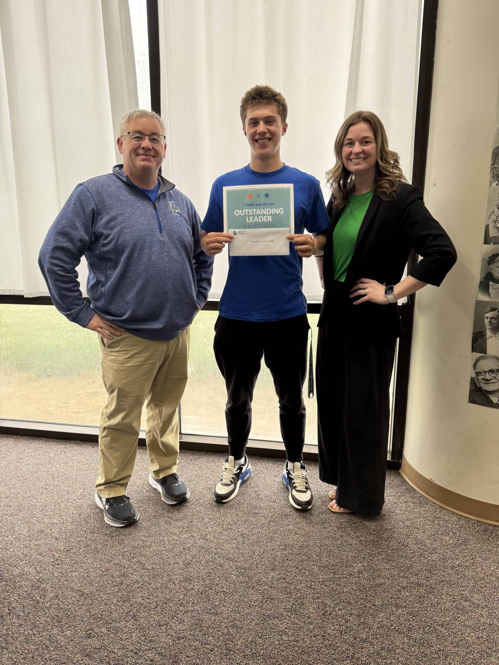 Smiling student in blue shirt holding 