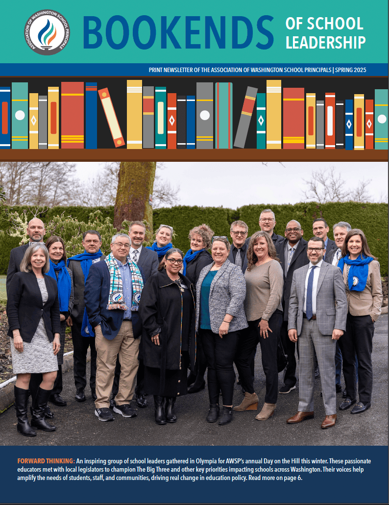 Group of school leaders posing outdoors, dressed in winter attire, in front of trees and shrubbery.