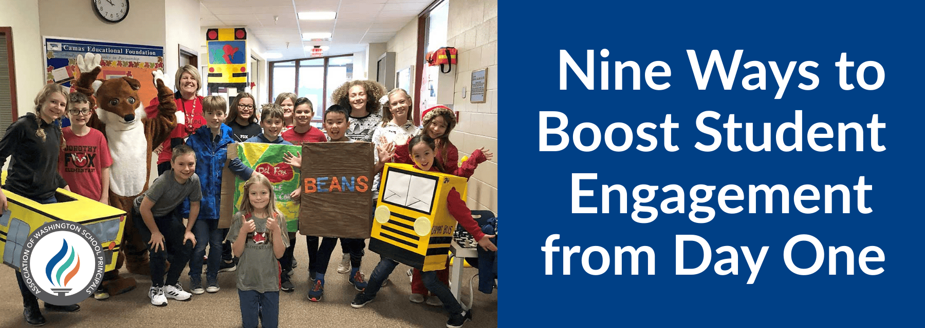 Group of smiling students and teacher in costumes, including buses, beans, and a fox mascot, in a school hallway.